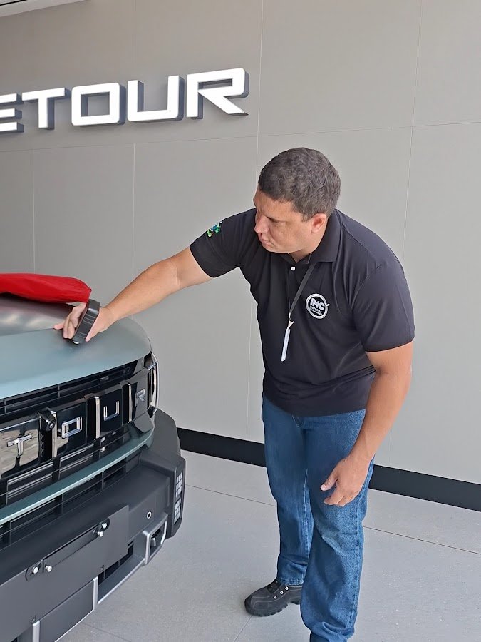 Inspetor da IMC Vistorias verificando o capô de um carro verde