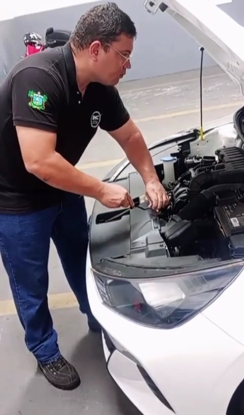Inspetor da IMC Vistorias verificando o motor de um carro branco