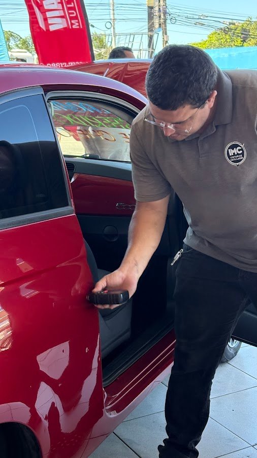 Inspetor verificando detalhes da porta de um carro vermelho
